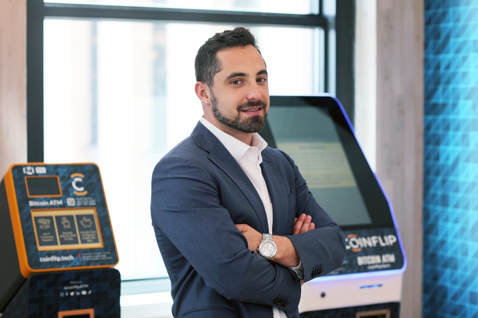 CoinFlip CEO Ben Weiss posing with arms crossed in front of CoinFlip ATMs